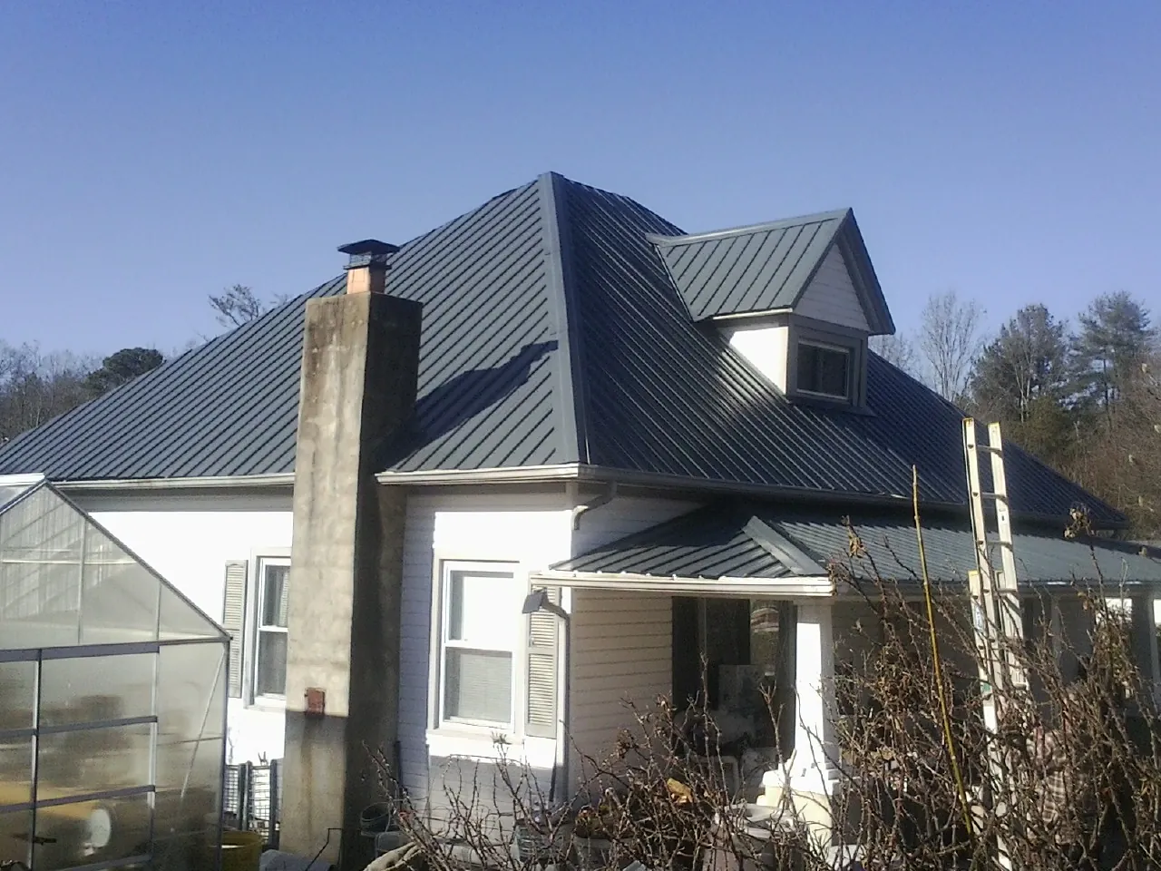 Dark blue standing seam metal roof on a white farmhouse with dormer — Slate & Tile Roof Repair by Roofing Brothers in Millheim