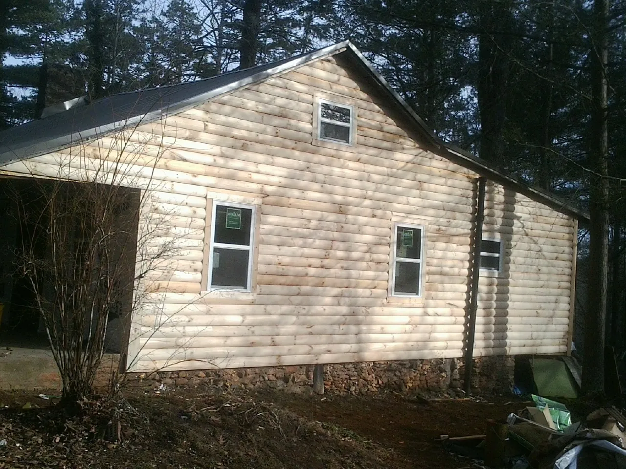 New log siding and dark metal roofing on a gable end in Millheim