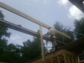 Carpenter setting a ridge beam over a new addition frame — Ice Dam Removal by Roofing Brothers in Millheim