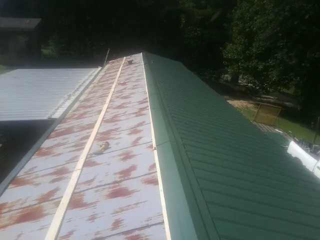 Old rusted panels beside newly installed green metal roofing — Wind Damage Roof Repair by Roofing Brothers in Millheim