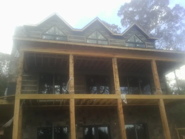 Dormers and porch framing on a large log home under construction — Roof Coating work by our crew in Millheim