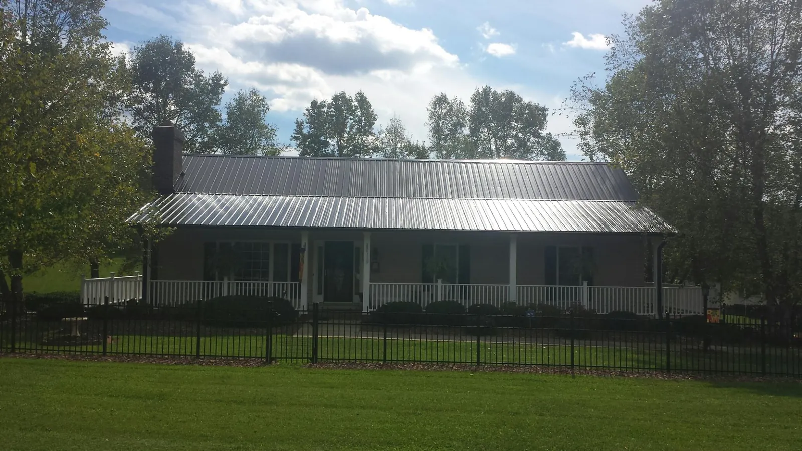 Gray metal roof on a brick ranch with a full width front porch — Gutter Guard Installation work by our crew in Millheim