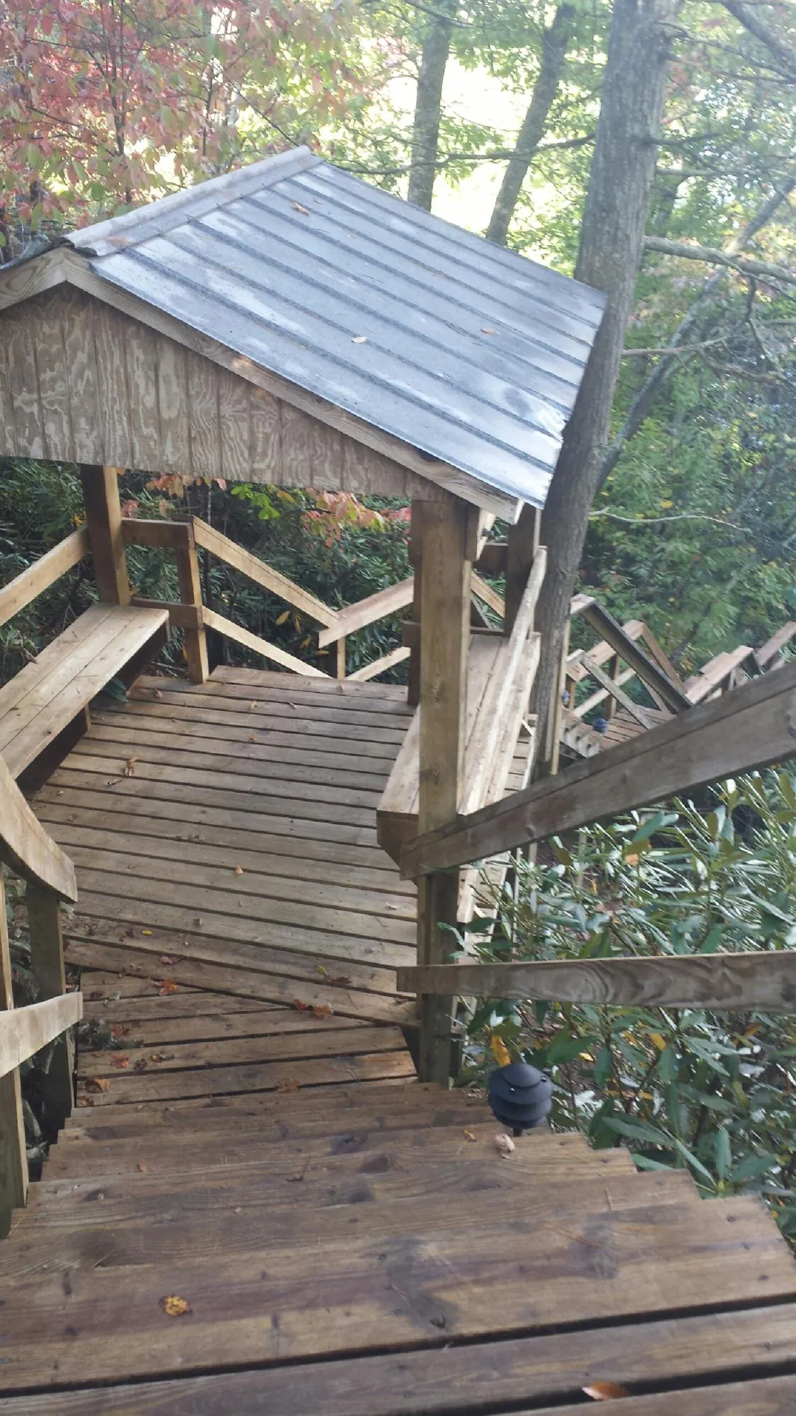 Metal roofed shelter over wooden steps on a wooded walkway — Skylight Repair & Installation work by our crew in Millheim