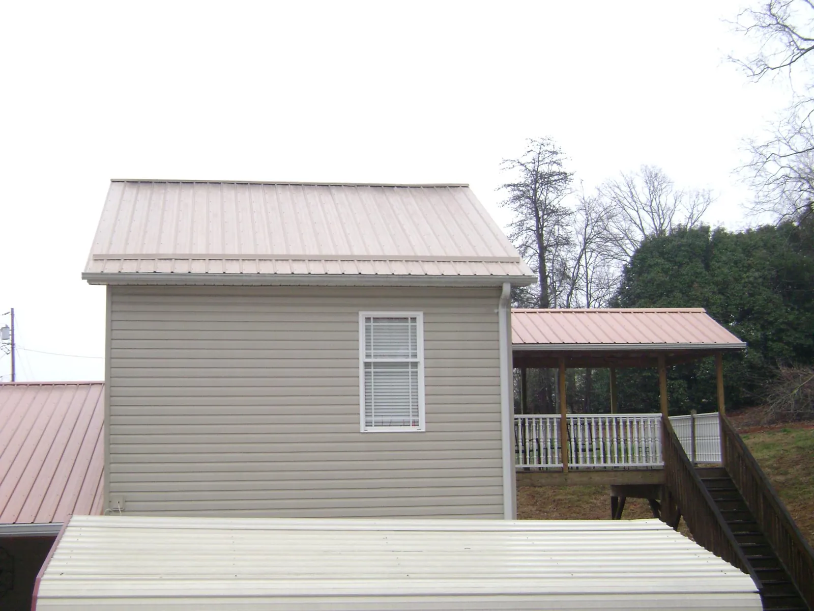Tan metal roofs on a two story addition and attached porch, from a Roof Replacement job in Millheim