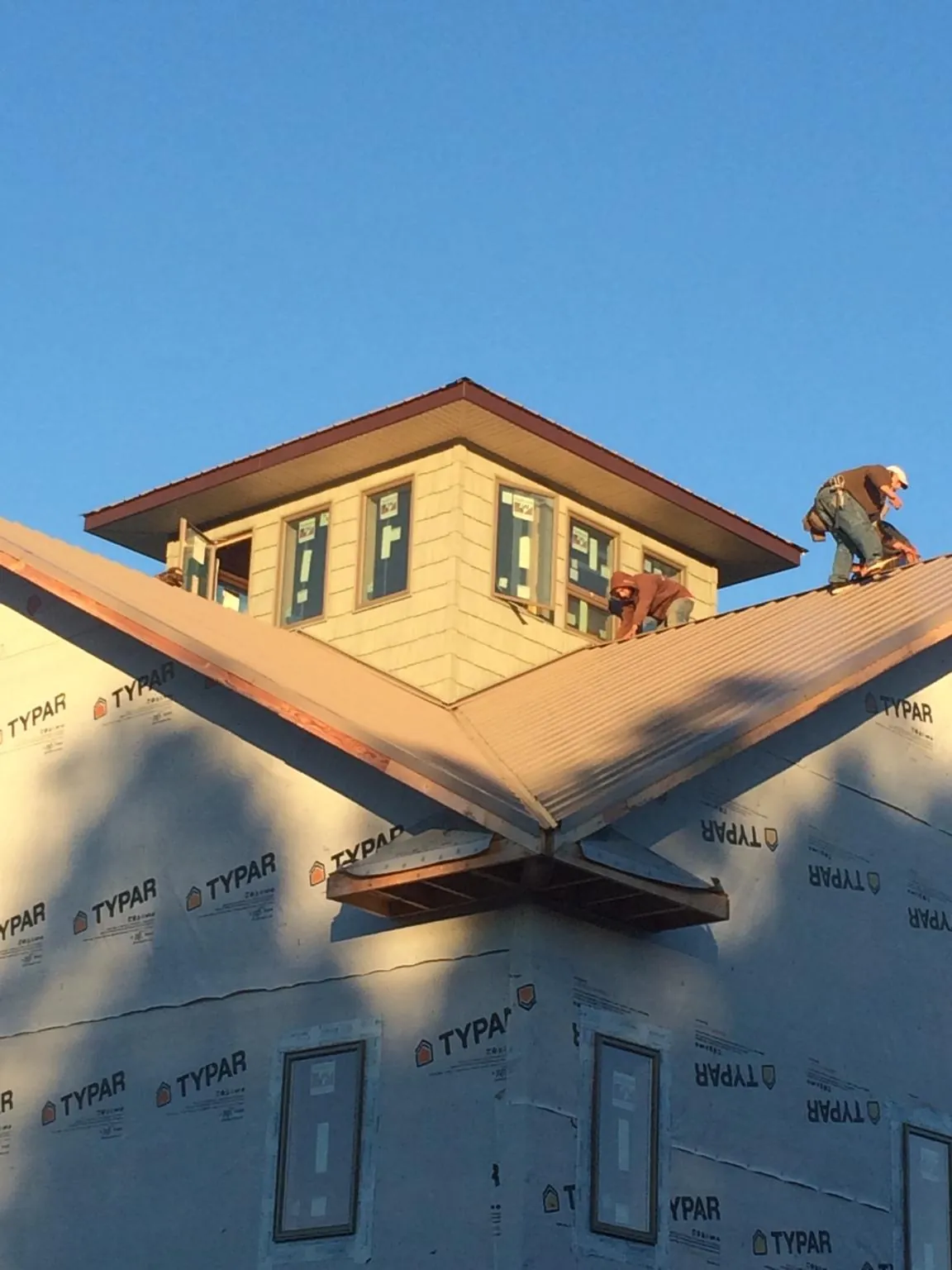 Roofers working around a rooftop cupola on a new metal roof at sunset — Roof Waterproofing in Millheim by Roofing Brothers